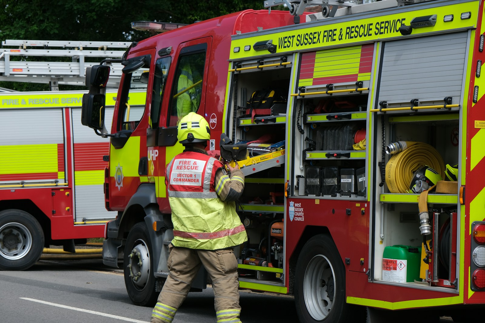 A firefighter retrieving equipment from a red fire truck