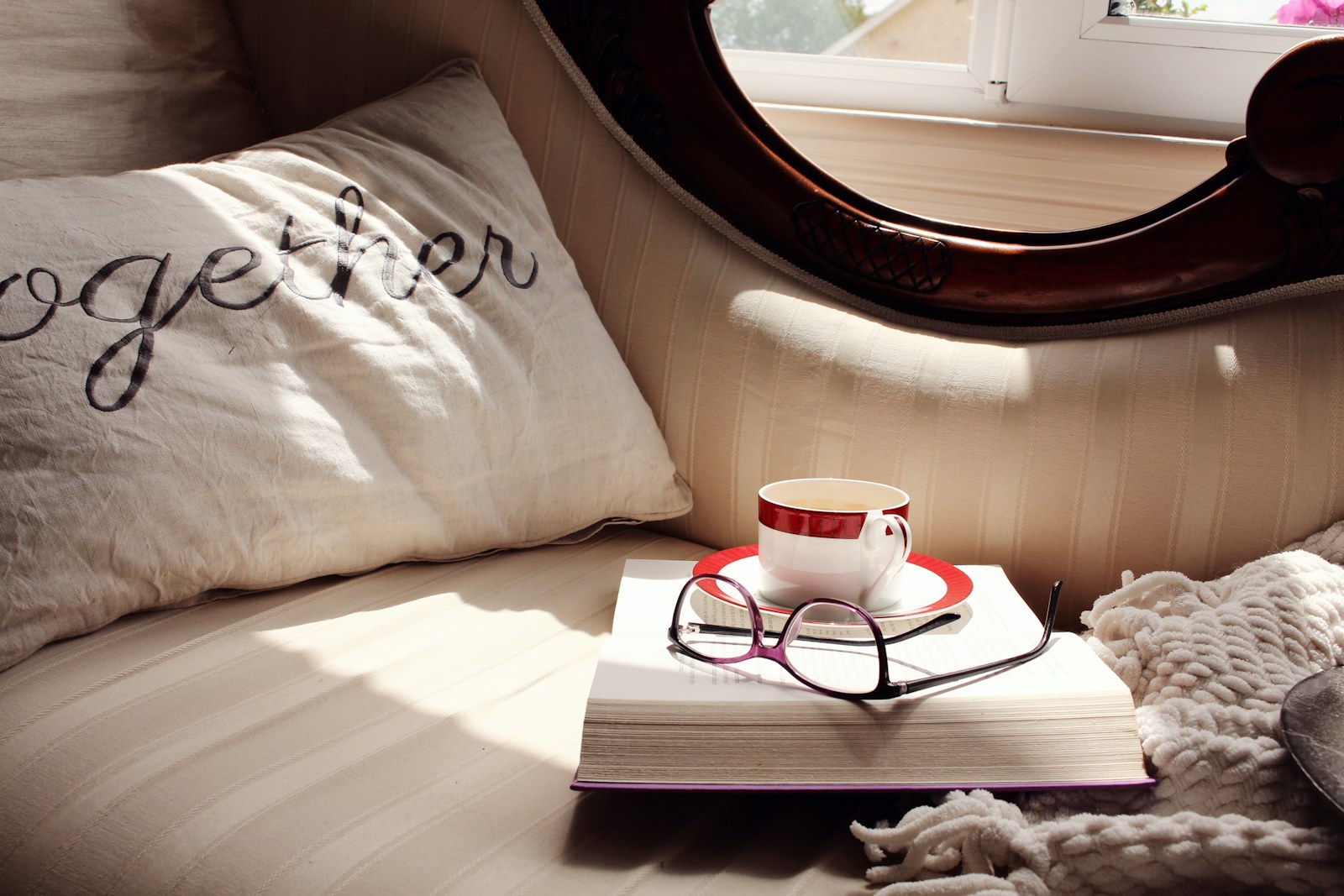Coffee cup, book, and eyeglasses on a cozy sofa