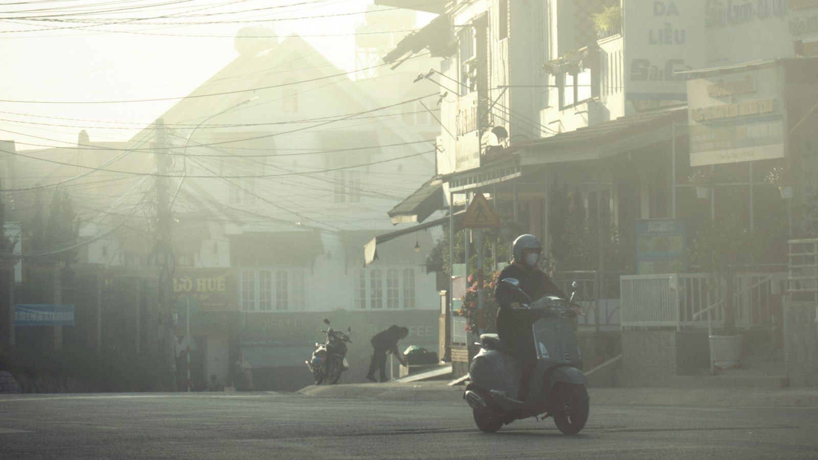 A person rides a scooter on a hazy city street