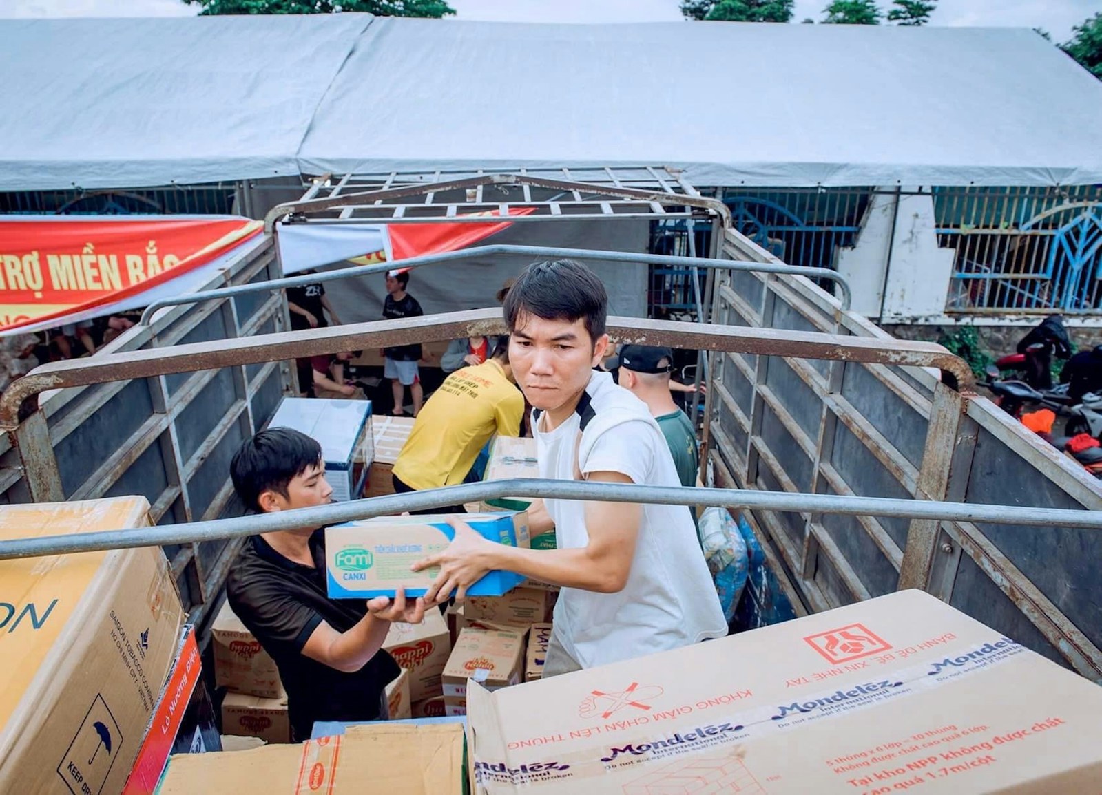 Two men loading cardboard boxes into the back of a truck