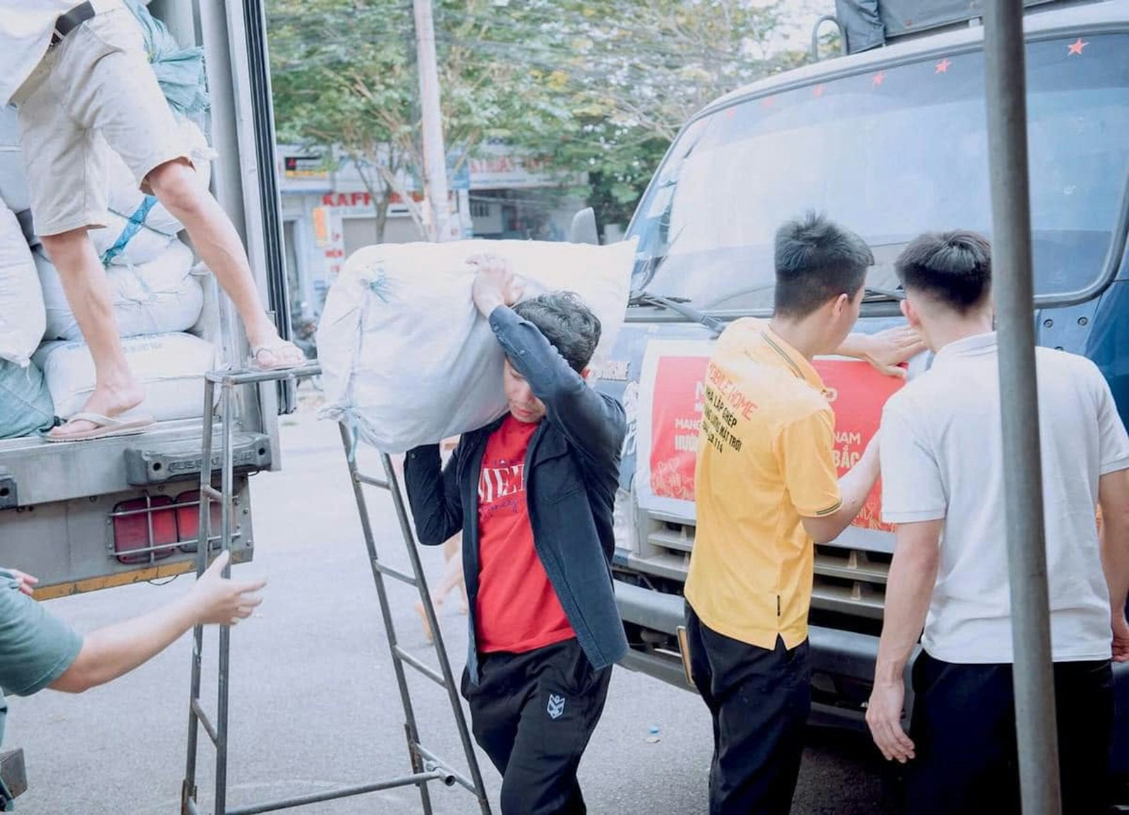 People loading white sacks into a truck on a city street