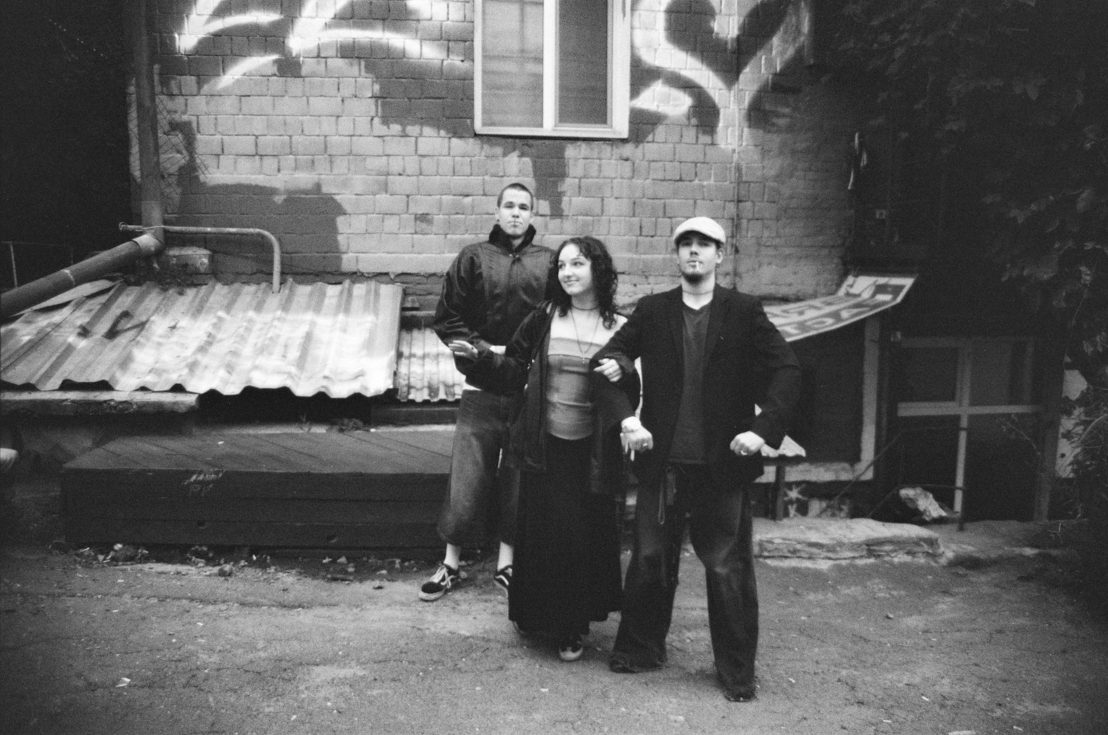 Three people standing in an urban alleyway