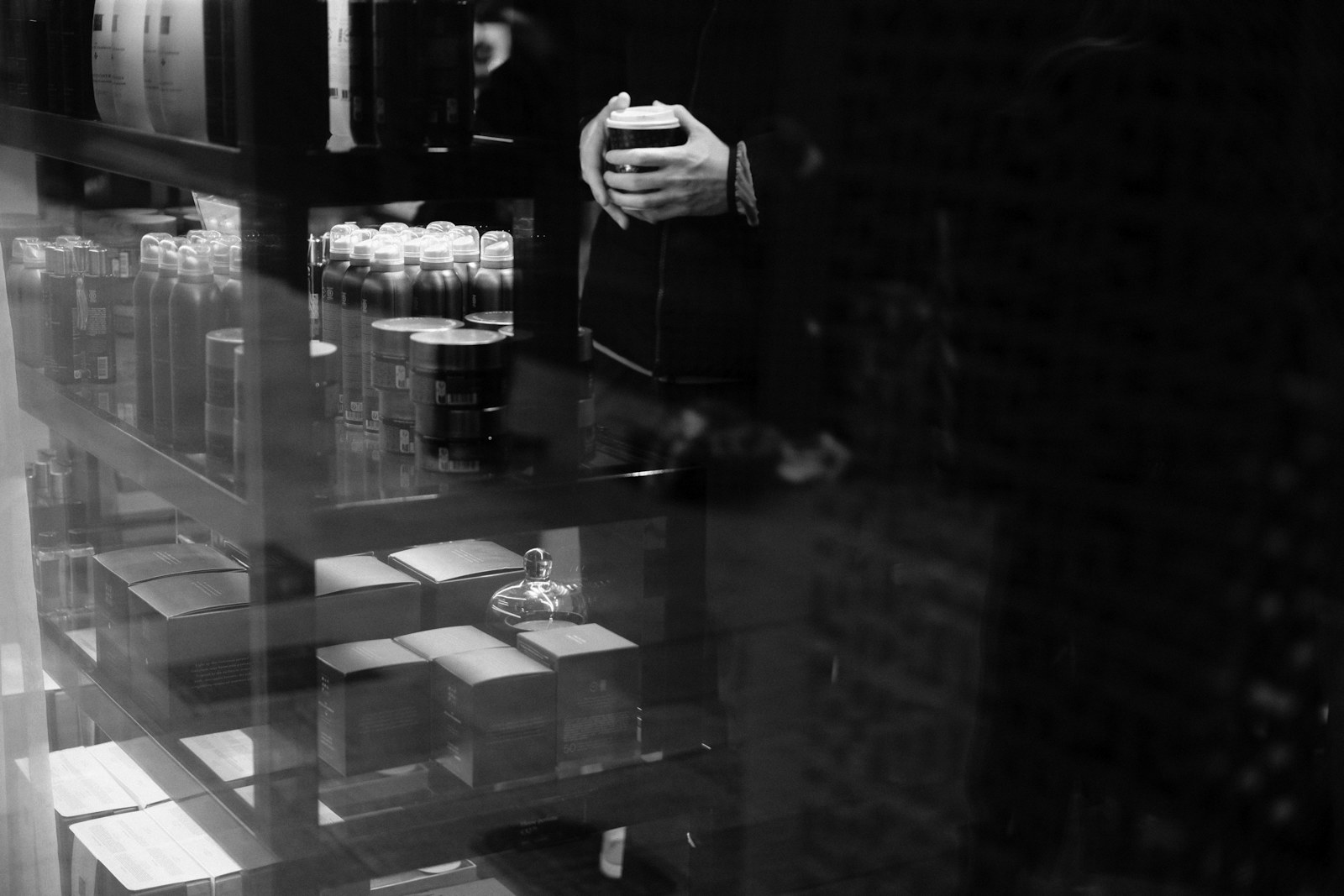 A person holding a drink inside a dimly lit establishment
