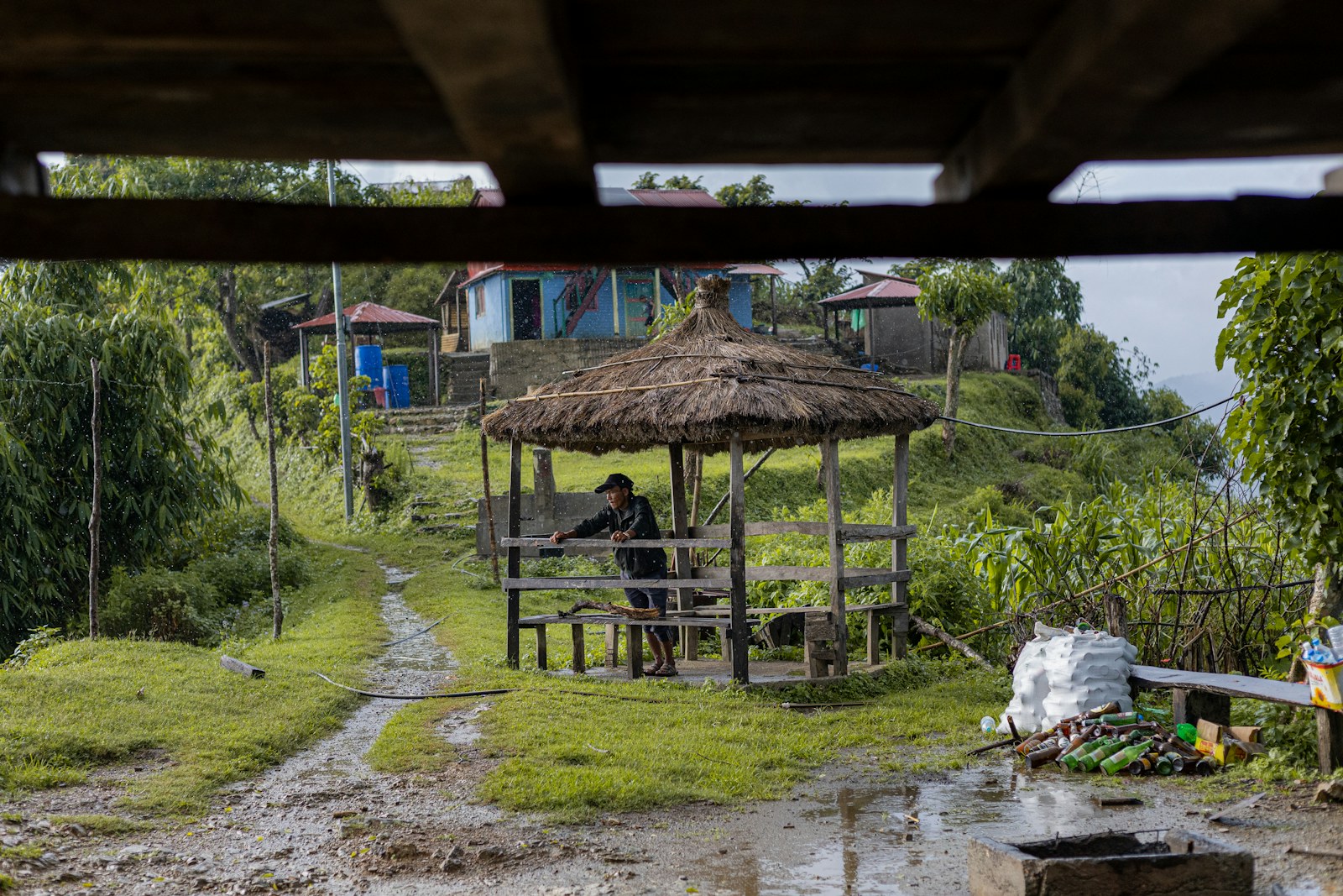 Person in a thatched-roof shelter in a rural village